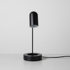 Black 16-inch LED desk lamp with attached cord trailing naturally across a neutral desk