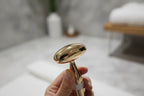 In-hand close-up of the Galahome gold-plated sonic facial massager head with shallow depth of field
