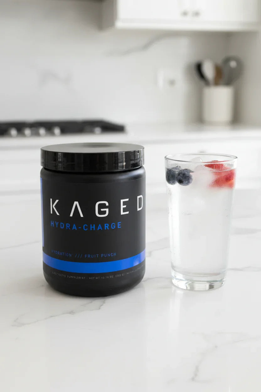 Kaged Hydra-Charge Fruit Punch tub on white quartz kitchen island next to iced water glass garnished with berries