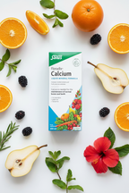 Salus Floradix Calcium Liquid Mineral Formula 250ml box flat lay with fresh pears, oranges, blackberries, hibiscus blooms, and green herbs on a white surface – More4less Outlet