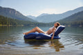 Intex Floating Recliner Lounge woman sunbathing on calm mountain lake pine trees sunny summer day