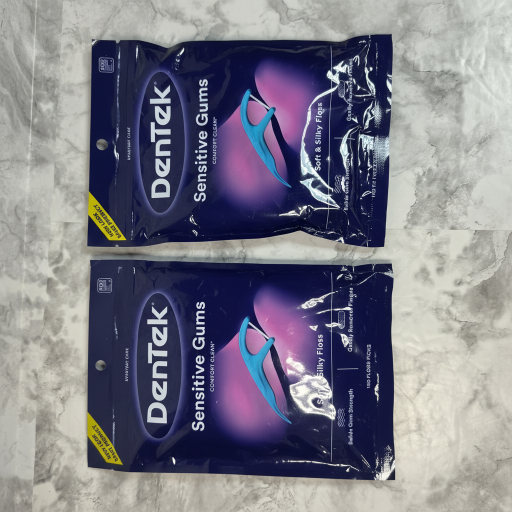 Two sealed DenTek Sensitive Gums Comfort Clean floss pick bags on a marble surface