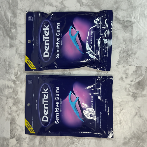Two sealed DenTek Sensitive Gums Comfort Clean floss pick bags on a marble surface