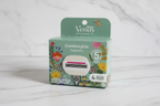Gillette Venus Comfortglide Sugarberry Rifle Paper Co. 4-count refill box held against white marble tile — sage green with colorful botanical floral illustration