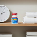 Aleve 220mg Naproxen Sodium 200ct bottle on wooden shelf in organized master bathroom closet with white towels and minimalist clock