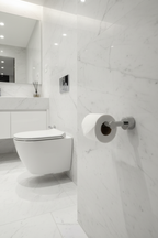 Grohe Atrio SuperSteel matte toilet paper holder with toilet paper roll mounted on white marble bathroom wall next to modern toilet