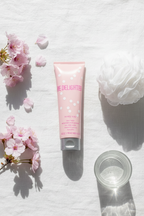 Mary Kay Be Delighted Body Wash 4 fl oz flat lay on white linen with pink flowers and loofah – More4less Outlet