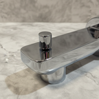 Grohe Lineare StarLight chrome tub spout close-up showing pull diverter knob detail and geometric rectangular body on neutral stone tile