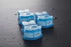 Macro focused tabletop shot of blue electric shaver cleaning refill cartridges on dark stone background