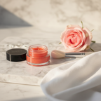 Mary Kay Cheek Glaze Tangerine clear jar on white marble vanity beside makeup brush pink rose and soft white linen
