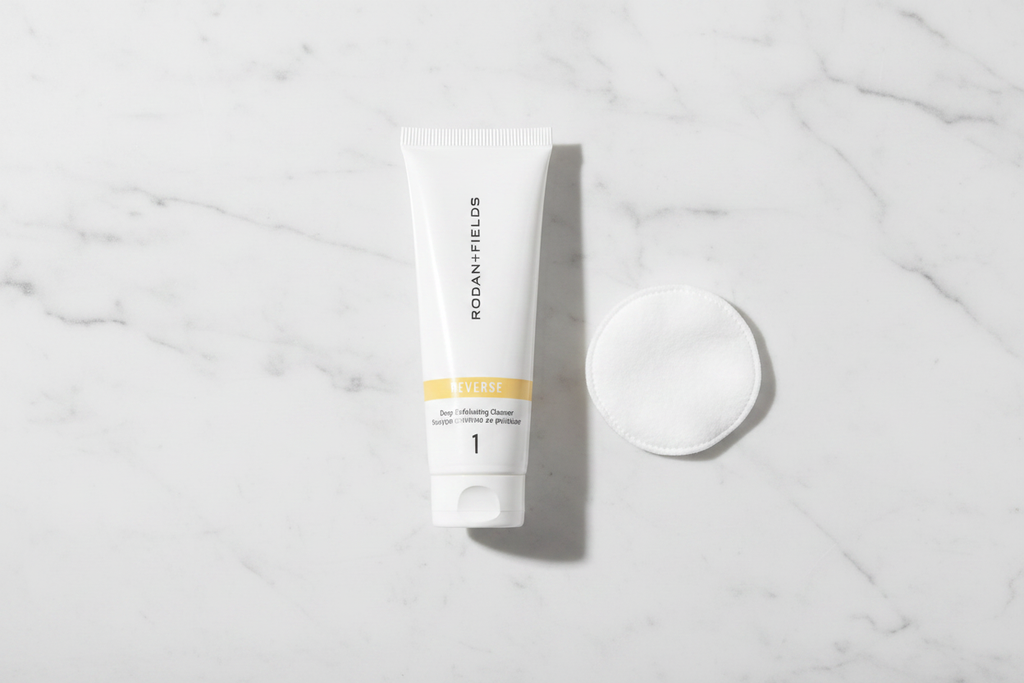 Rodan + Fields REVERSE Deep Exfoliating Cleanser 30mL tube in morning skincare flat lay with cotton pad on white marble