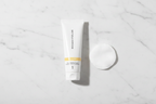 Rodan + Fields REVERSE Deep Exfoliating Cleanser 30mL tube in morning skincare flat lay with cotton pad on white marble