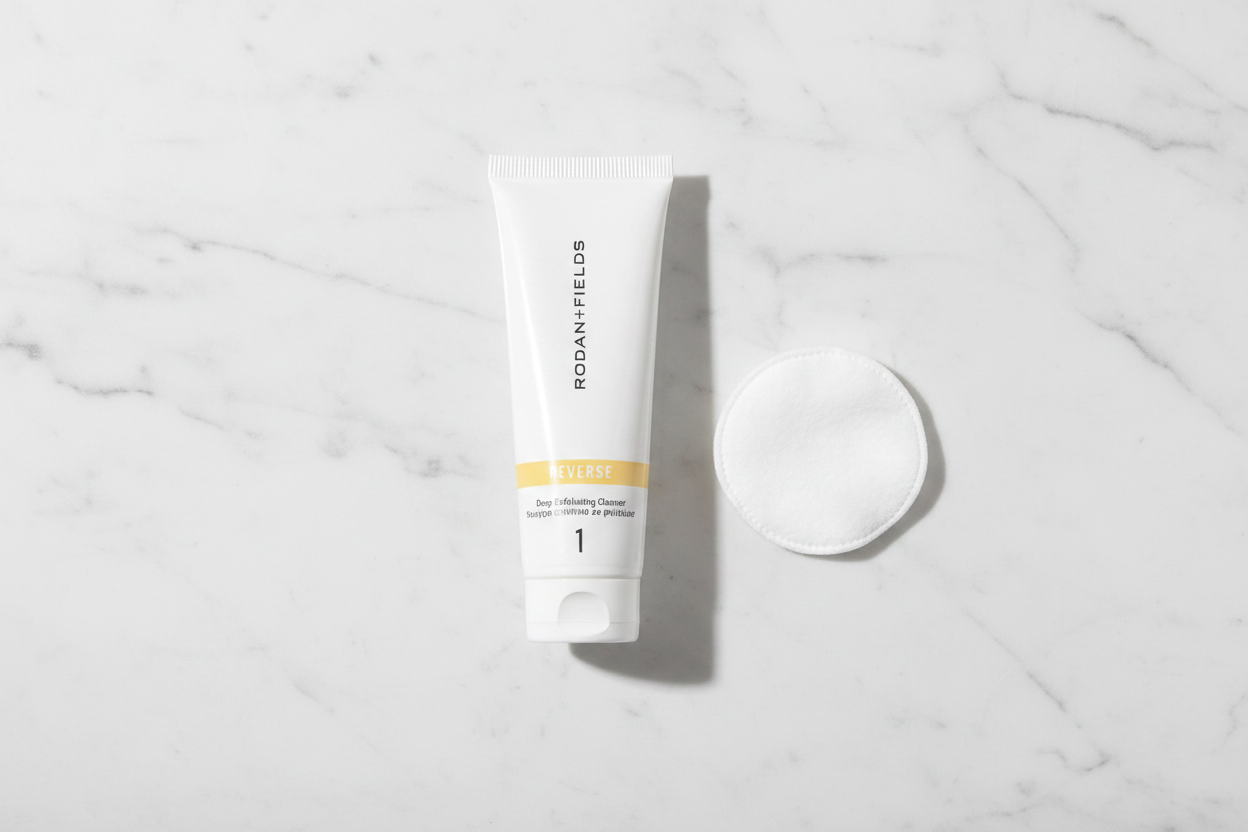 Rodan + Fields REVERSE Deep Exfoliating Cleanser 30mL tube in morning skincare flat lay with cotton pad on white marble