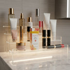 Burt's Bees Truly Glowing Glow Booster box in organized skincare acrylic shelf with high-end designer cosmetics against neutral bathroom background