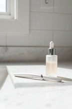 Gillette Venus facial razor on white quartz vanity with glass serum dropper