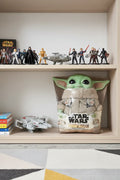 Star Wars Mandalorian Squeeze and Blink Grogu plush on organized modern child's playroom shelf with soft bright lighting