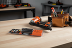 Paslode 902654 7.4V Li-Ion battery pack on workbench beside finish nailer and tool belt - More4less Outlet