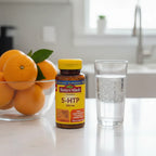 Nature Made 5-HTP 100mg Chewable bottle on white quartz kitchen counter with fresh oranges and sparkling water
