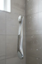 Close-up of a high-quality platinum metal razor handle in a bright modern shower setting