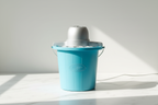 Nostalgia blue vintage-style 4-quart electric ice cream maker on white marble surface in natural sunlight
