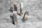 Professional flatlay of three Gillette Venus Daily Soothing Serum bottles with retail cartons on white marble in bright natural daylight