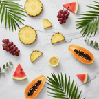 Flat-lay of fresh AHA fruit ingredients — pineapple, papaya, lemon, grapes, and watermelon — on white marble