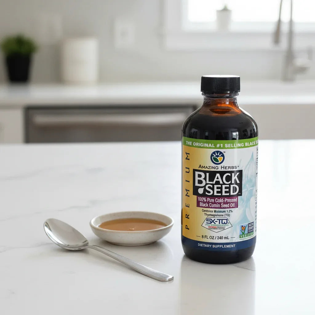 Amazing Herbs Black Seed Oil bottle on white quartz kitchen island with stainless steel teaspoon and dish of raw honey