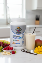 Garden of Life Sport Organic Plant Protein vanilla tub beside creamy vanilla shake with vanilla pods on marble surface