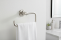 Brushed nickel towel ring mounted on a white textured wall in a minimalist modern bathroom