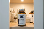 BioCare Caprylic Acid 90ct amber glass bottle in bathroom health cabinet with premium skincare and wellness items — clinical supplement storage display