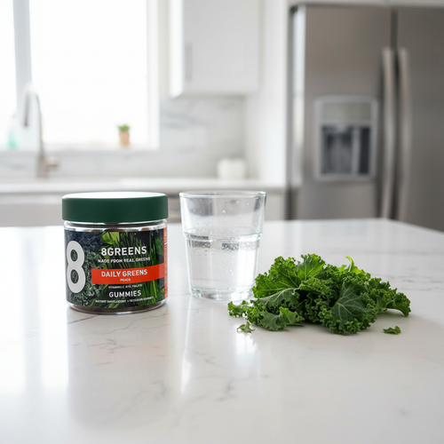 8Greens Daily Greens Peach Gummies jar on white quartz breakfast island with glass of water and fresh kale leaves