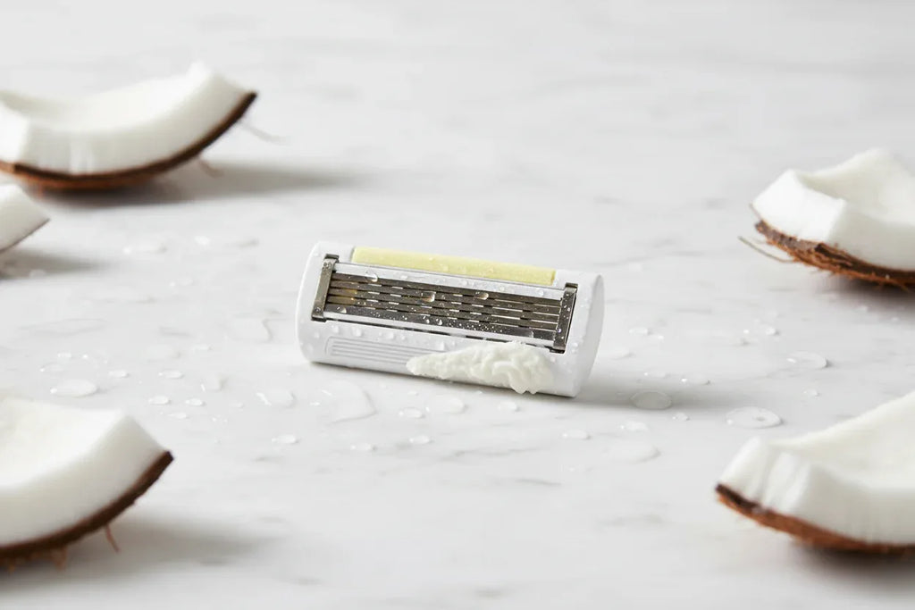 Close up of a women's razor cartridge refill on clean white bathroom marble with coconut accents