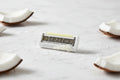 Close up of a women's razor cartridge refill on clean white bathroom marble with coconut accents