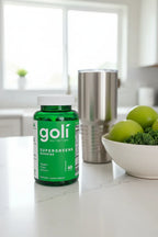 Goli Supergreens Gummies jar on white quartz kitchen island with silver coffee tumbler and bowl of green apples and kale — More4less Outlet