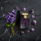 Lifestyle — deep purple perfume bottle on dark marble beside wild violet flowers, black feather, and scattered amethyst crystals — bold editorial for visual context only