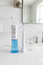 Miracle Smile Water Flosser standing upright on a white bathroom countertop next to a toothbrush and glass of water.