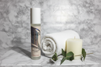 Gillette Venus Daily Soothing Serum slim pump bottle with holographic label next to white rolled towel, candle, and eucalyptus on marble spa surface in warm ambient light