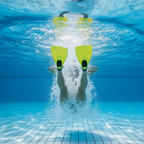 Close-up underwater shot of a young swimmer's feet performing a breaststroke kick with yellow training fins