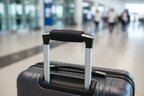 Black travel folding bag trolley sleeve sliding over telescoping handle of rolling suitcase