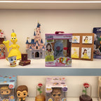 Real Littles Disney Beauty and the Beast Micro Journal on display shelf with other Disney collectibles and toys.