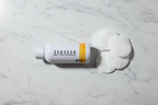 Rodan + Fields REVERSE Intensive Brightening Toner in minimalist spa flat lay with cotton pads on marble
