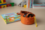 Planet Buddies Charlie the Tiger headphones stored in travel pouch beside colorful children's adventure book