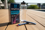 DripDrop Bold Variety Electrolyte Pack 8ct on sunny wooden deck with water bottle and stick packs — athletic hydration lifestyle