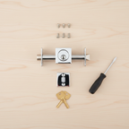 Flat-lay of Kwikset 816 SQT polished chrome deadbolt components on wooden workbench – cylinder, latch, strike plate, keys, screws, screwdriver