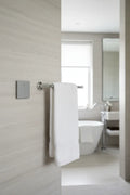 Legrand Adorne magnesium paddle switch installed on light-grey stone bathroom wall next to chrome towel bar