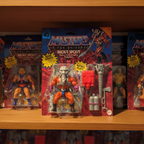 Masters of the Universe Origins Snout Spout figure displayed on a wooden collector shelf among other MOTU blister card packages — More4less Outlet