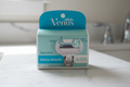Gillette Venus Deluxe Smooth Sensitive 4-count refill box on white marble bathroom counter in soft natural light