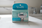 Gillette Venus Deluxe Smooth Sensitive 4-count refill box on white marble bathroom counter in soft natural light