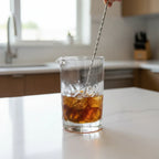 Silver One mixing glass with condensation being stirred on modern quartz kitchen island for mixology precision