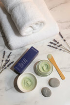 Relaxing spa-at-home setup with folded white towels and exfoliating facial treatment products on clean marble